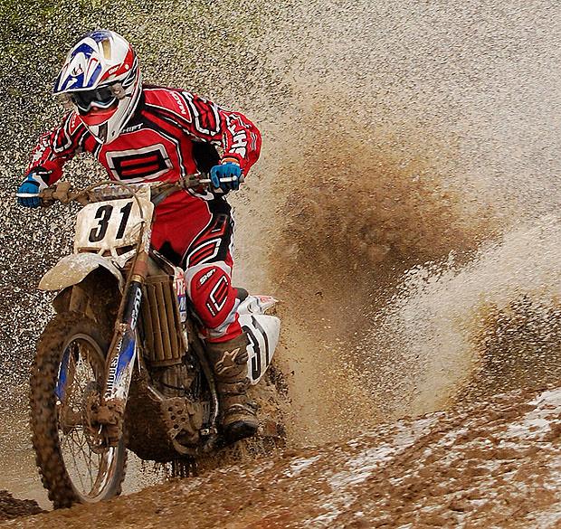Moto X rider splashing through muddy puddle