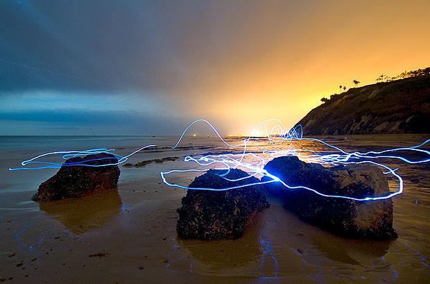 Light streaks around rocks on a beach at sunset