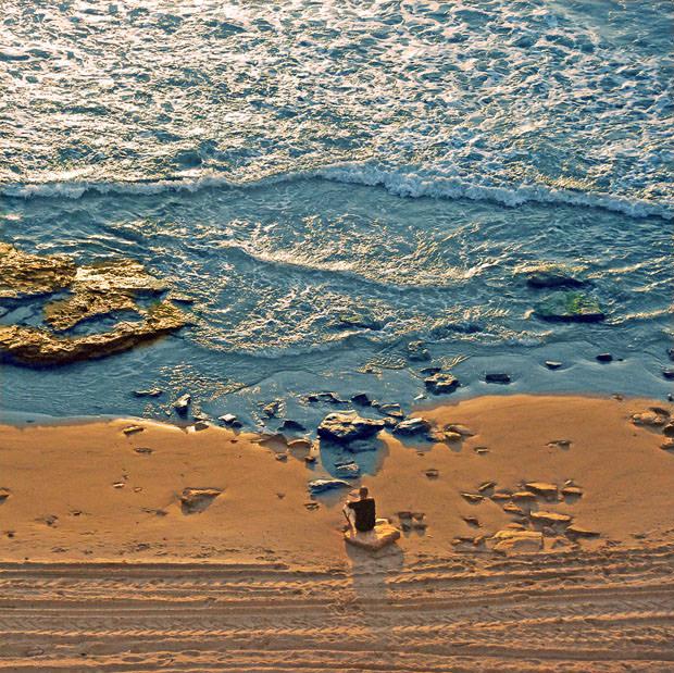 Man sitting on beach photographed from above