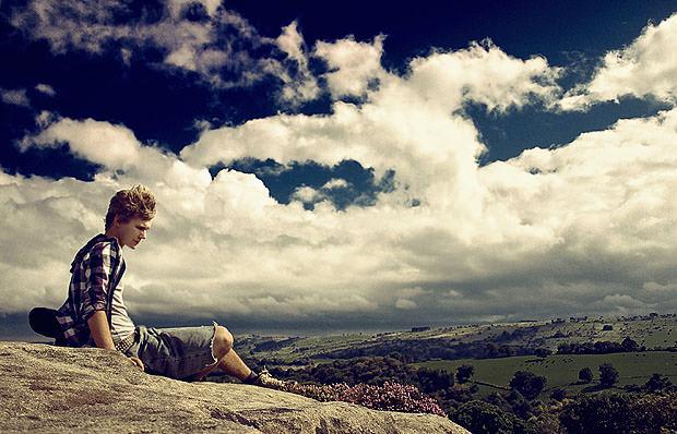 Man on rock in front of clouds