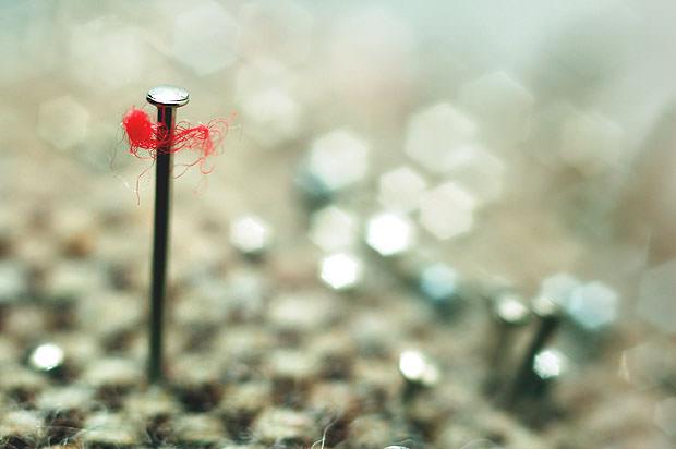Close up of a needle with a piece of red thread