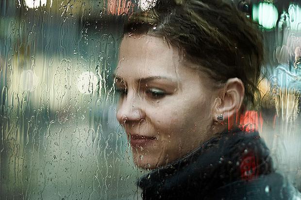 Woman behind glass with rain running down it