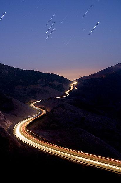 A winding road with car light trails